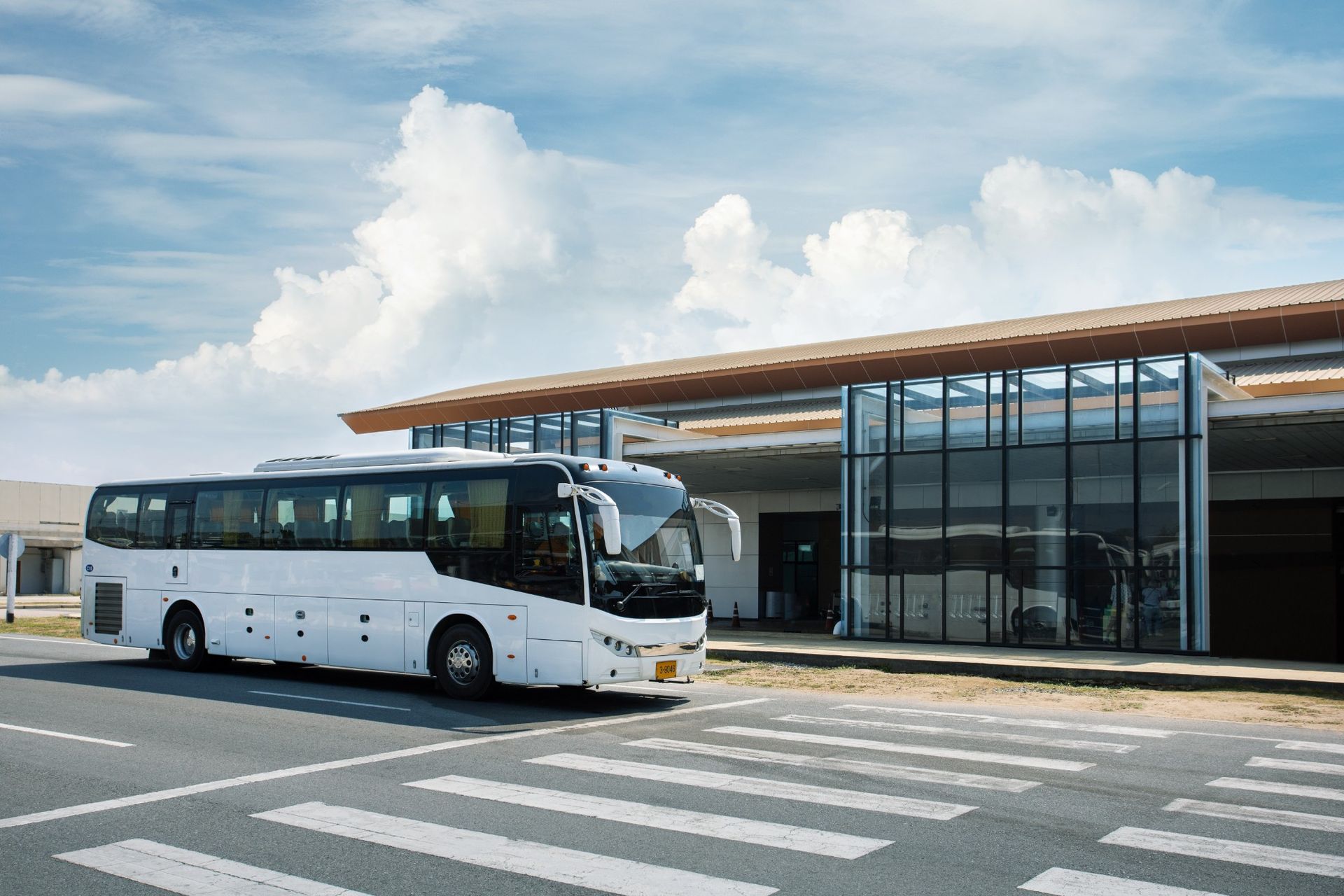 A white bus is parked in a parking lot in front of a building.