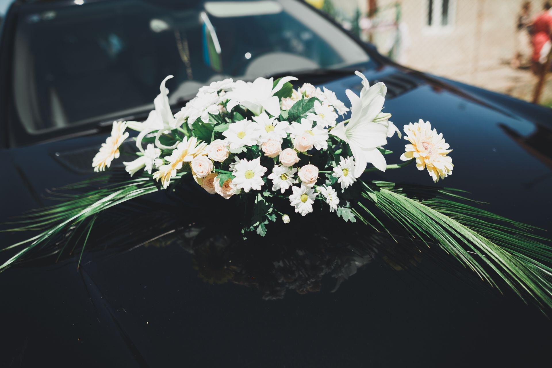 A black car with a bouquet of white flowers on the hood.