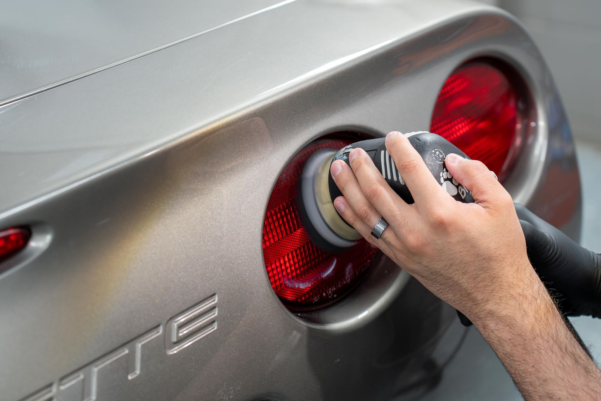 A person is polishing the tail light of a car.