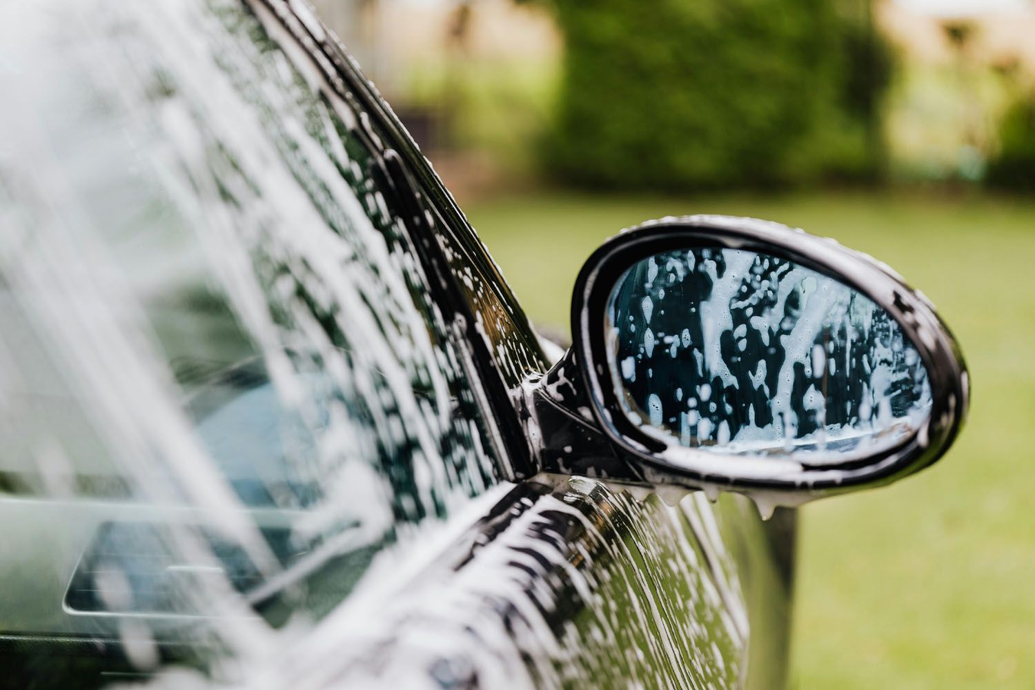 A close up of a car being washed with soap and water.