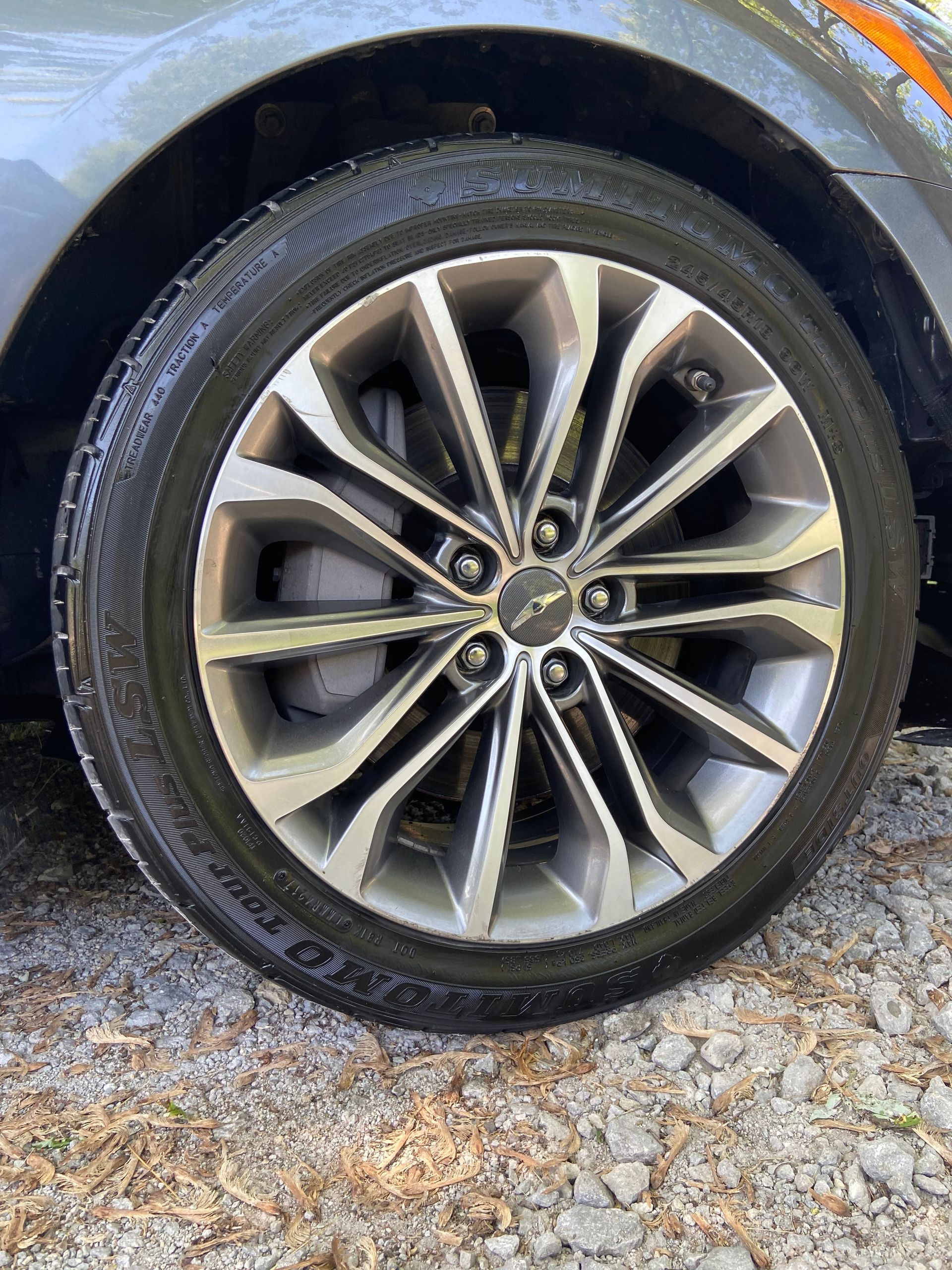 A close up of a car wheel on a gravel road.