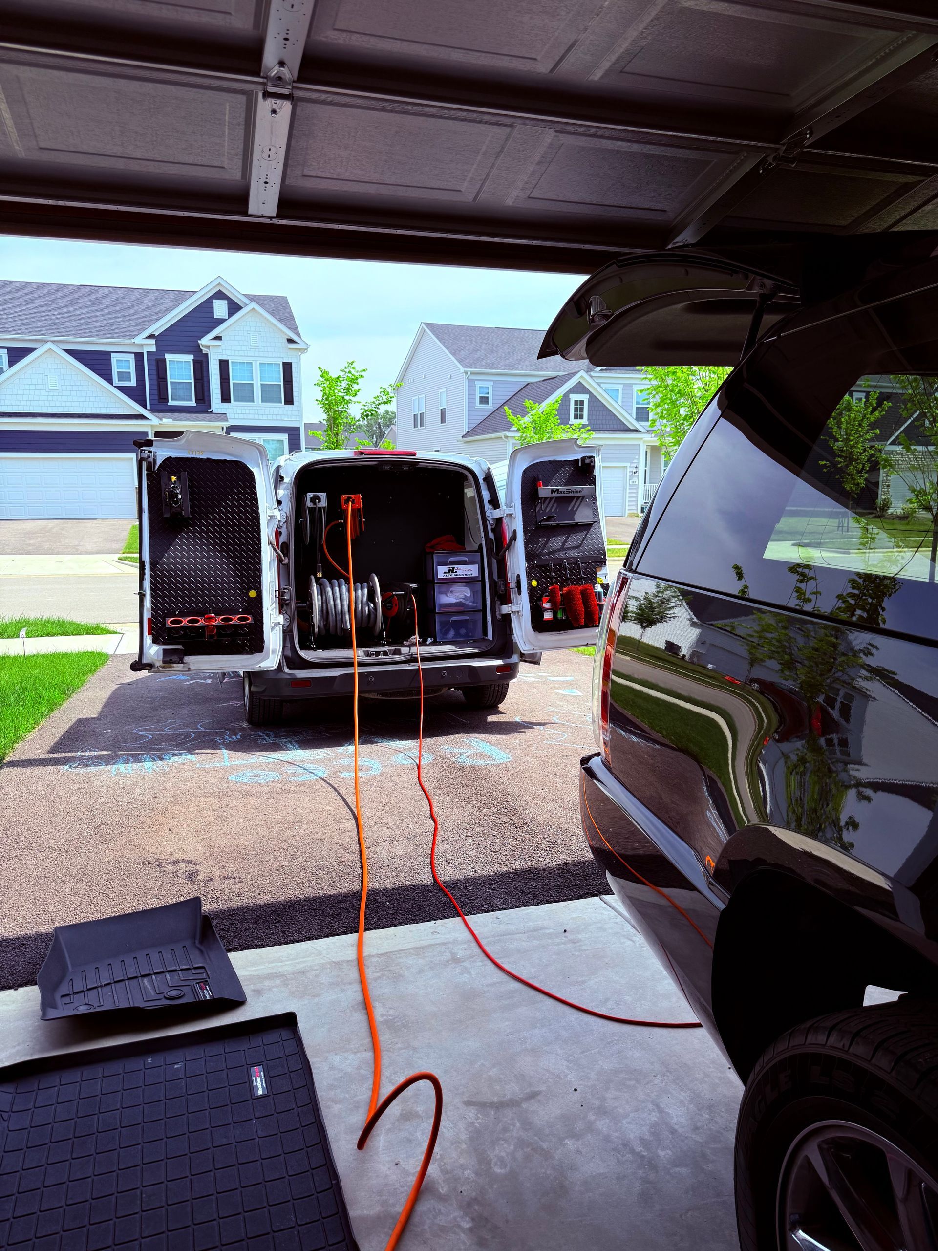 A black car is parked in a driveway next to a garage door.