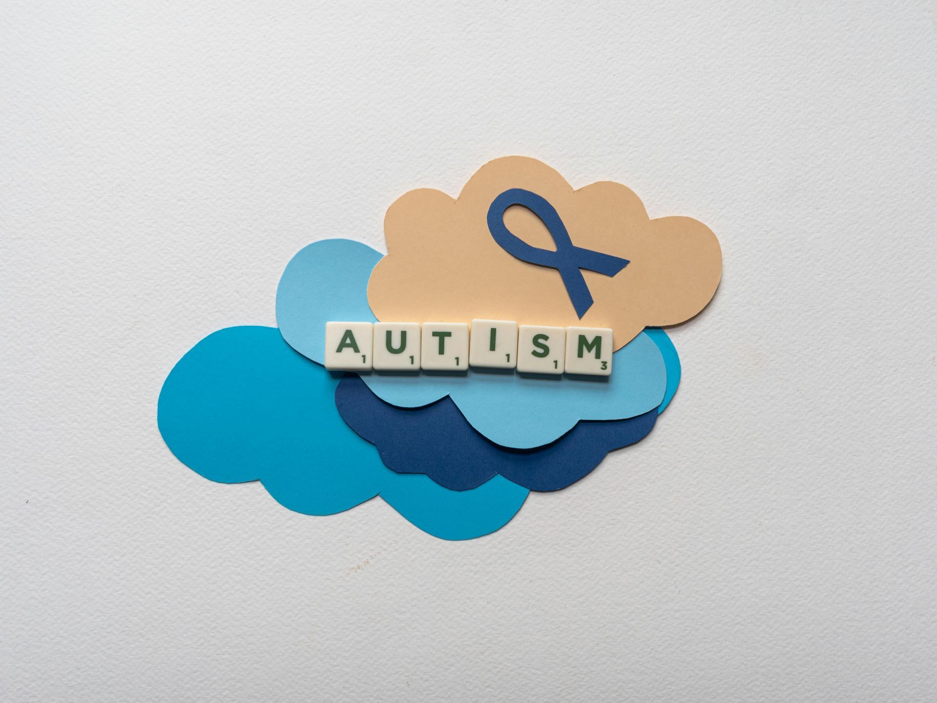 The word autism is written in scrabble tiles on a cloud.