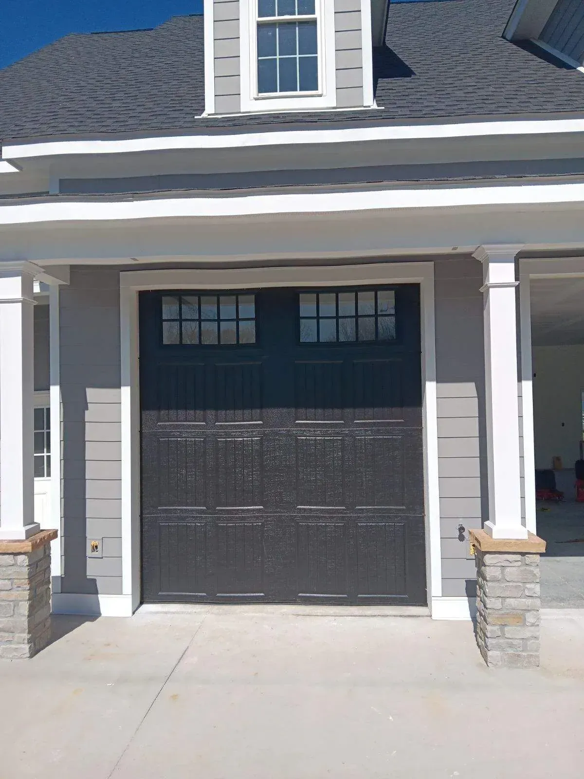 A black garage door is sitting in front of a house.