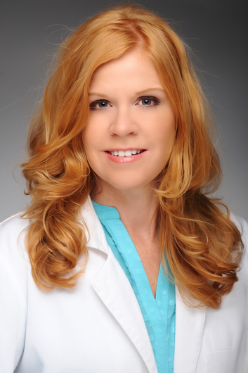 A man in a lab coat and tie is smiling for the camera