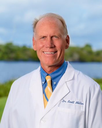 A man in a lab coat and tie is smiling for the camera