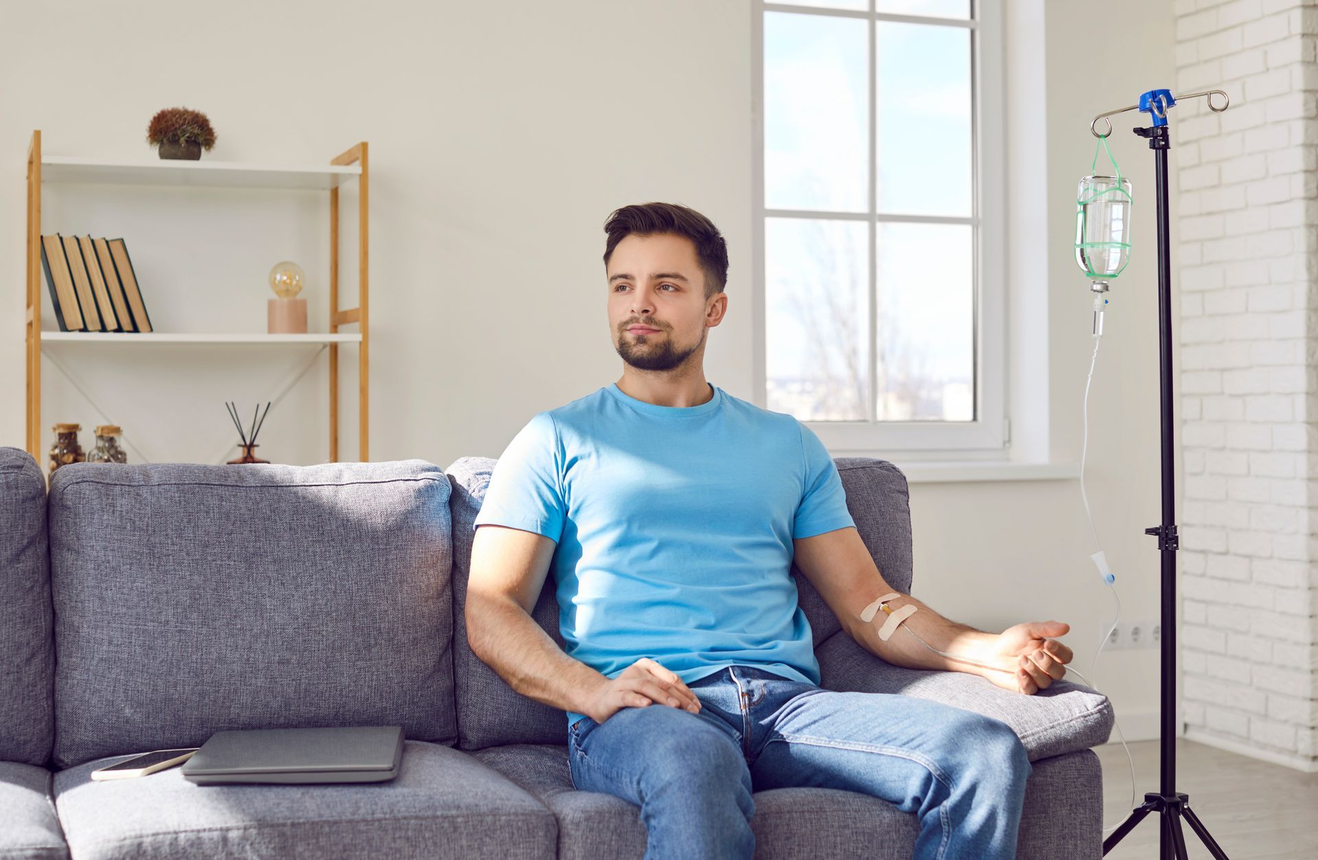 A man is sitting on a couch with an iv in his arm.