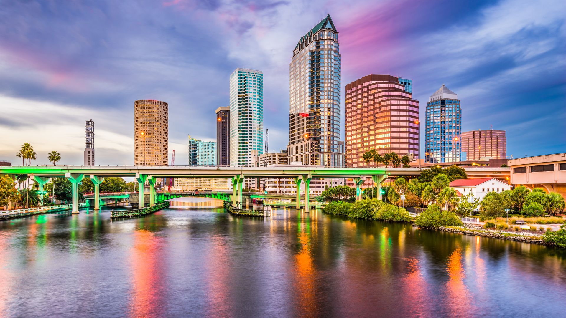 A bridge over a river with a city skyline in the background.