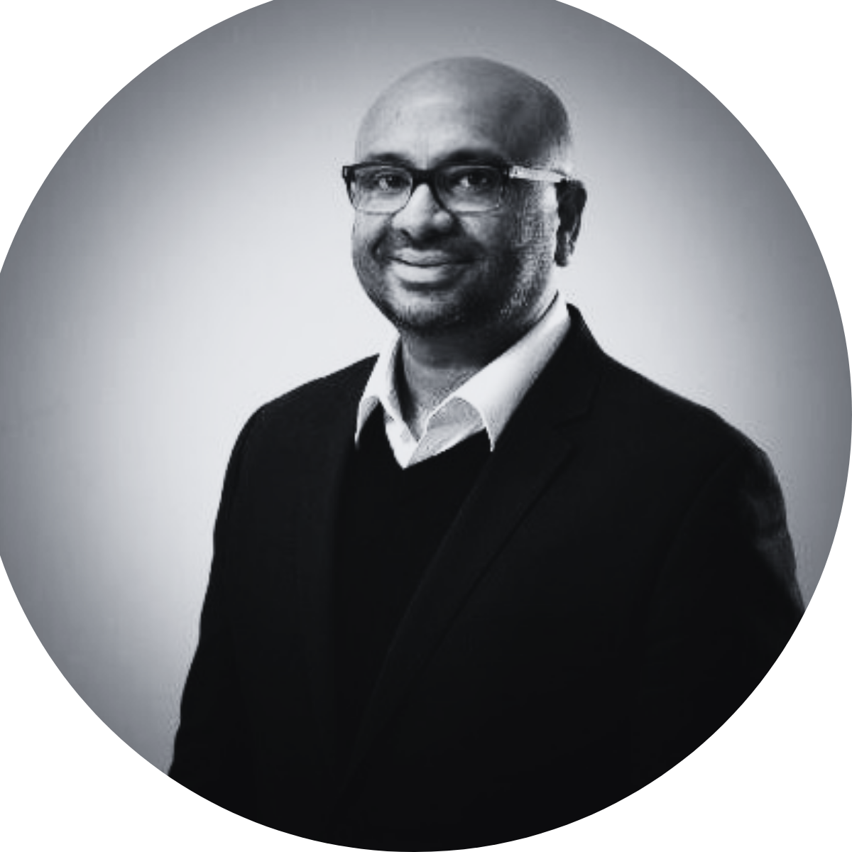 A black and white photo of a man wearing glasses and a suit