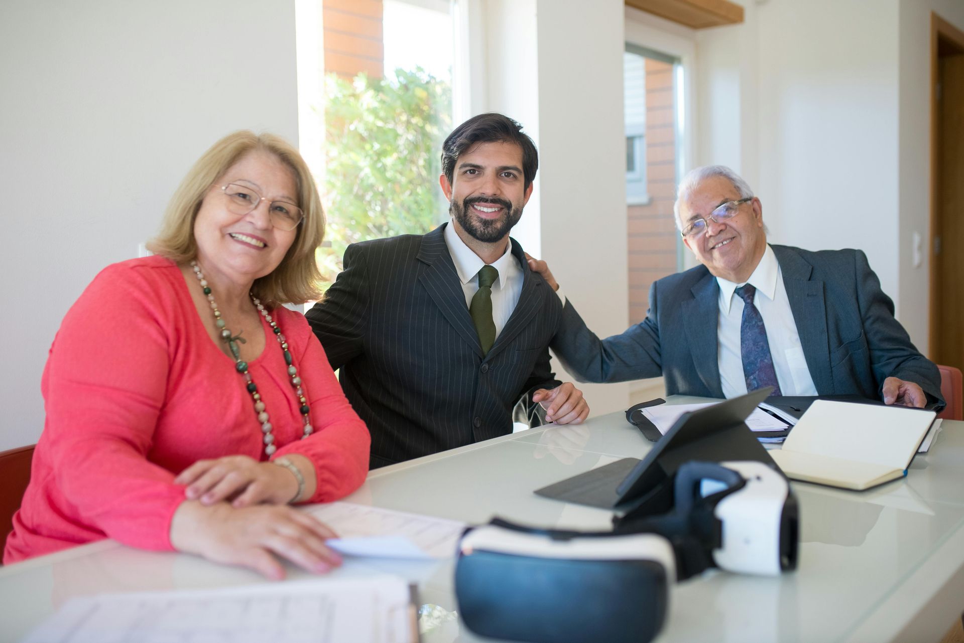 A man and a woman are sitting at a table with a virtual reality headset.