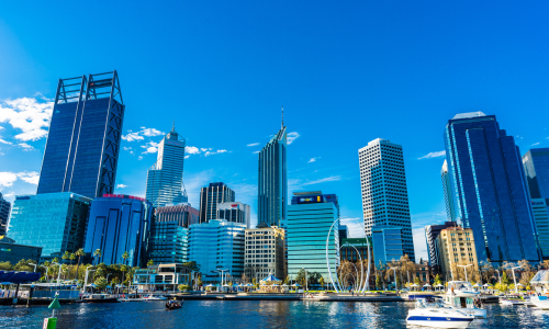 A city skyline with boats in the water in front of it on a sunny day.