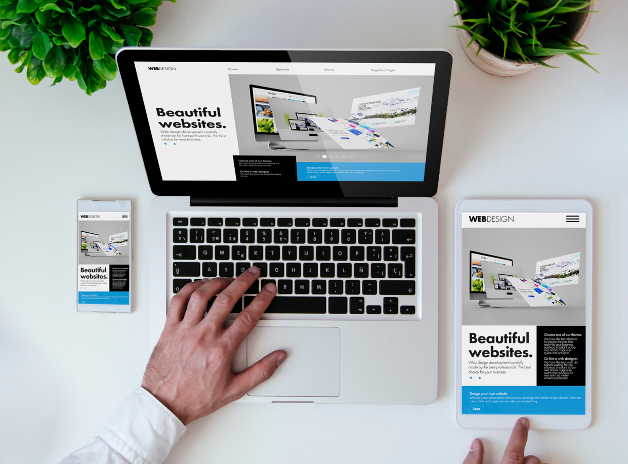 Office tabletop with tablet, smartphone, and laptop showing cool responsive design website