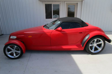 Red Plymouth Prowler convertible with a black top parked in front of a white building.