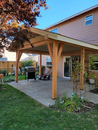 A wooden covered patio in the backyard of a house.