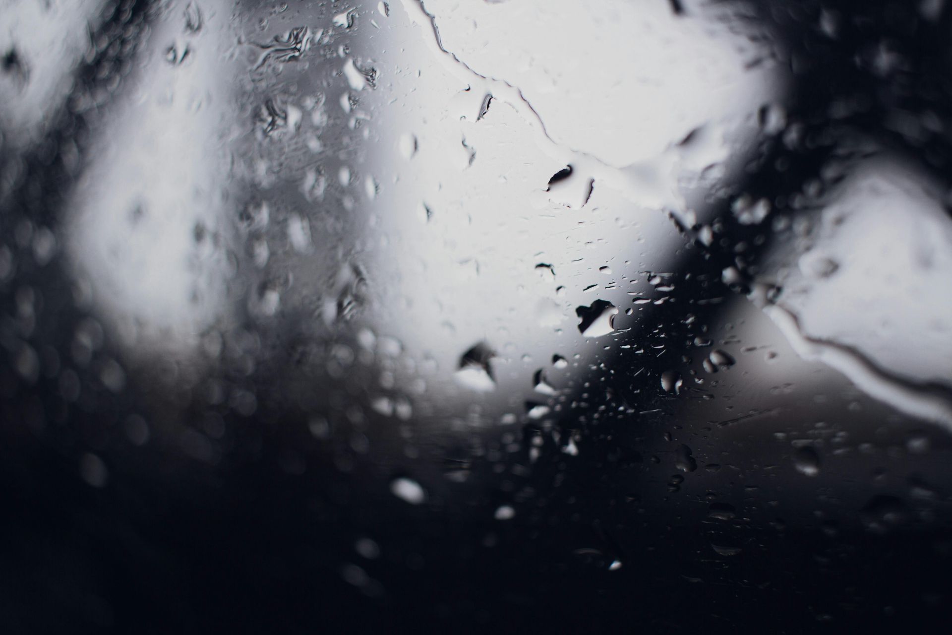 Raindrops on a window, blurred outdoor background.