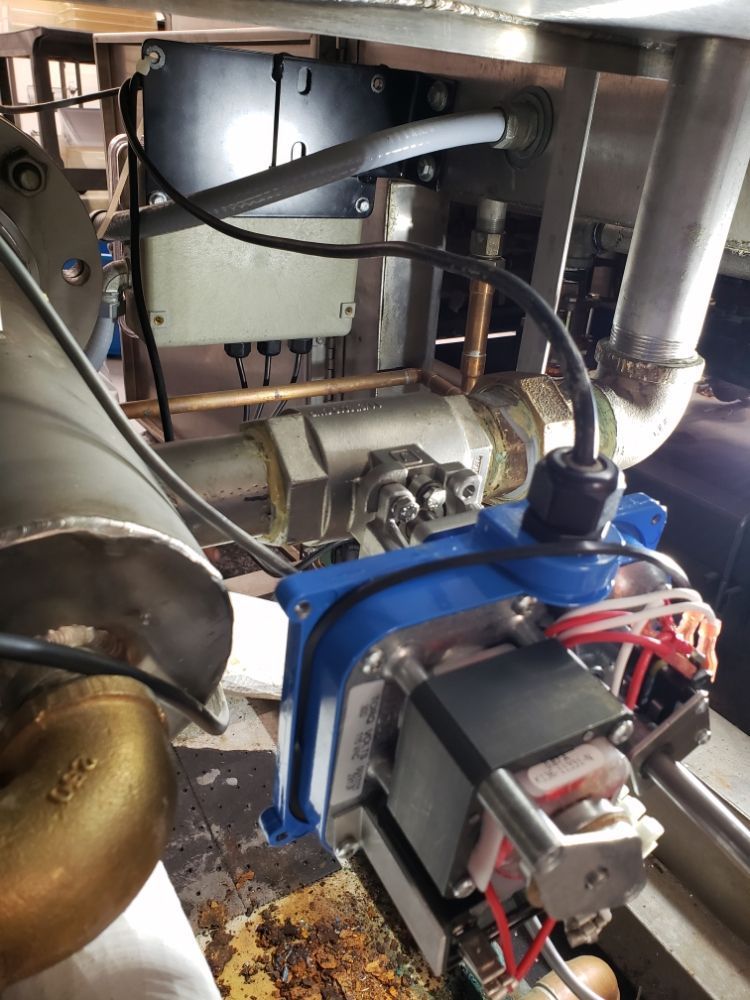 Close-up of industrial machinery components with pipes, valves, and electrical wiring.