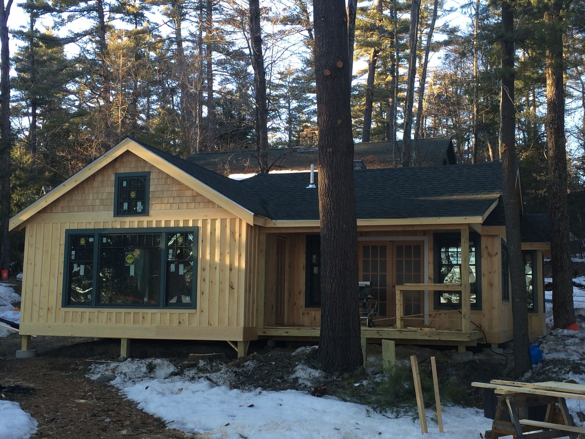 Close-up of a gray shingle roof on a house, with green trees and houses in the background.