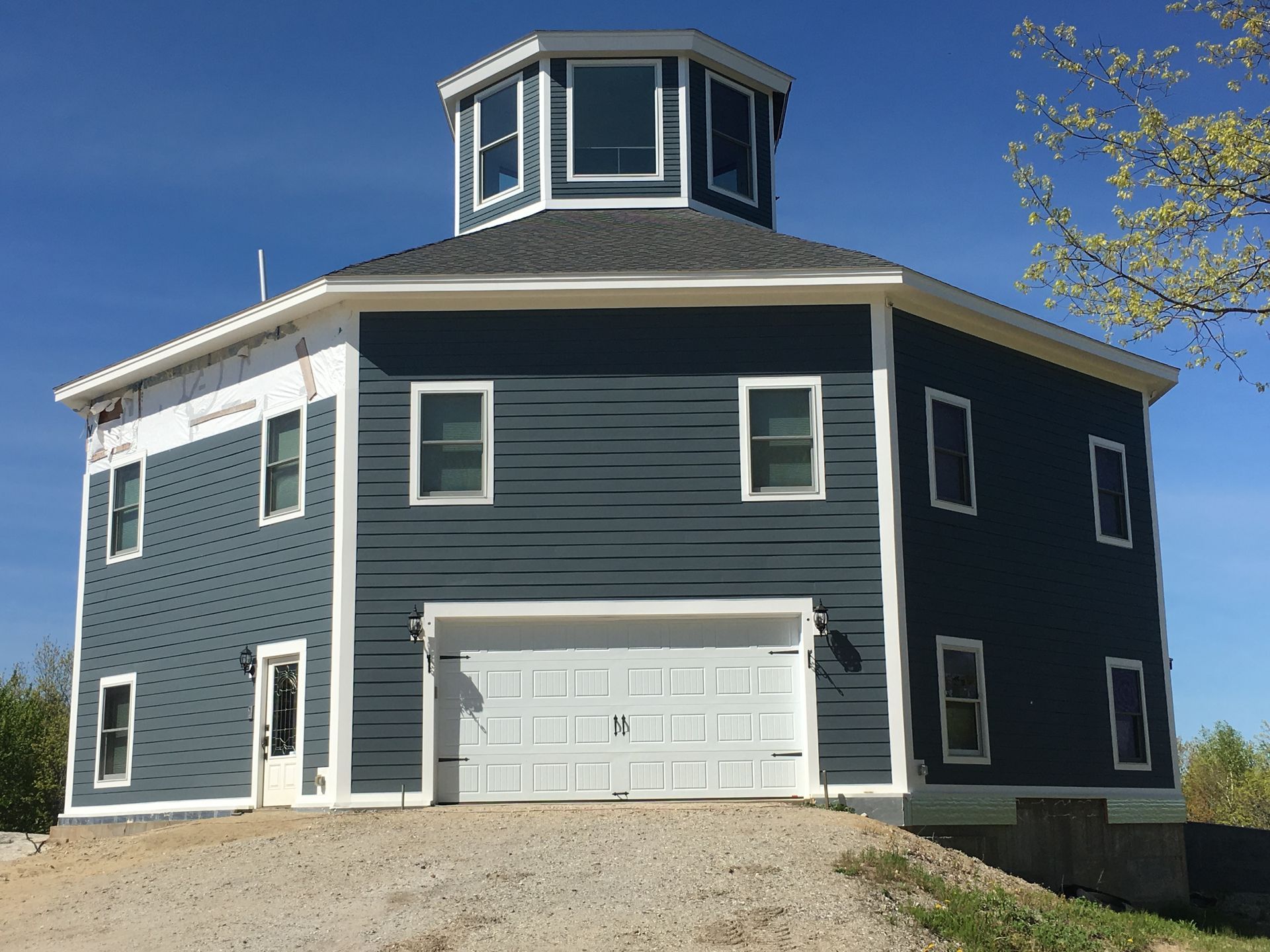 Brick cottage with slate roof, chimney, and green shutters.