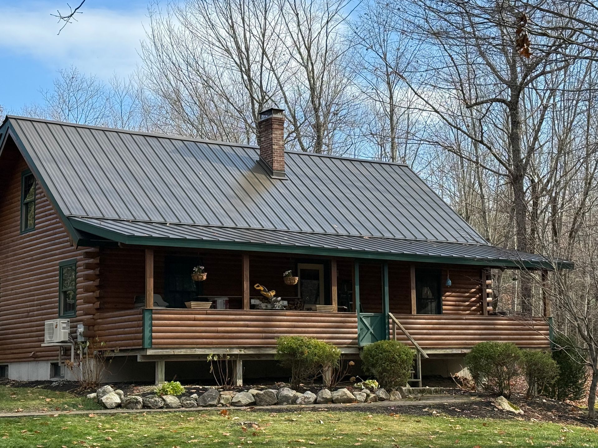 Roofer in hard hat installing a black roof vent on a shingled roof with houses in the background.