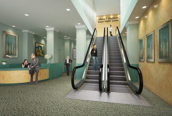 A lobby for the Adams T. Merchant Health Center with a reception desk, paintings, and central escalators leading upward.
