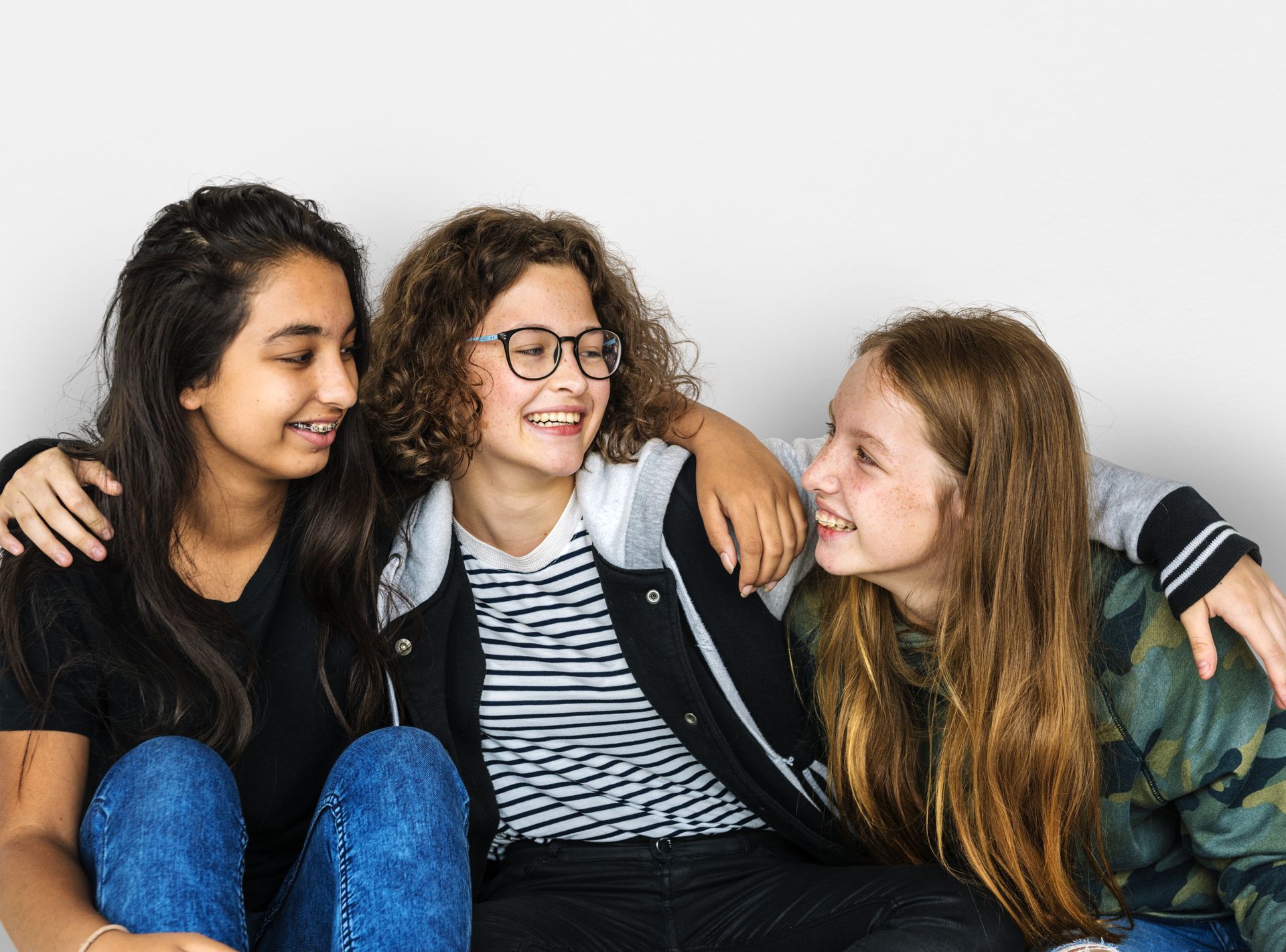 Three young girls are sitting next to each other on a couch.