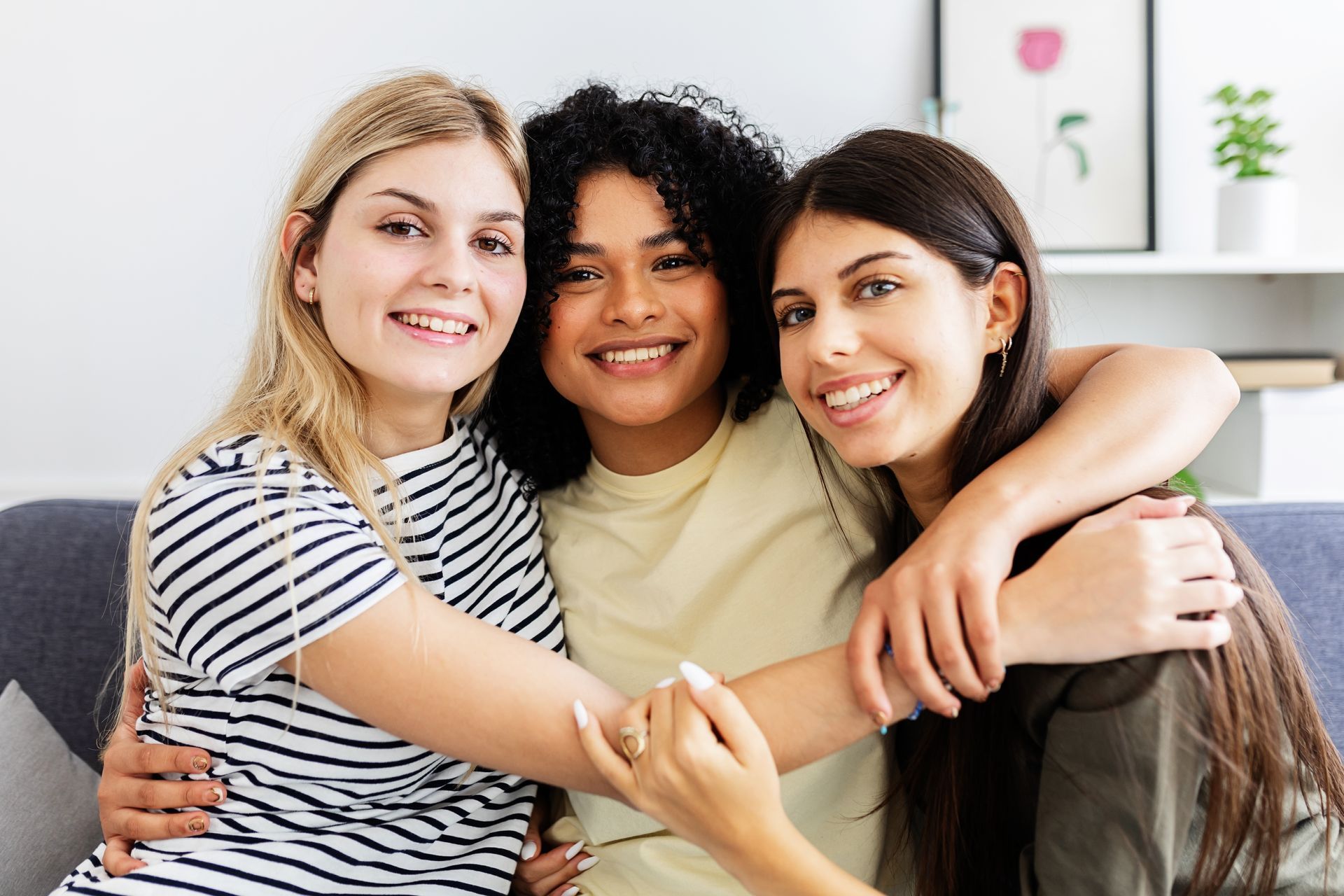 Three women are hugging each other while sitting on a couch.