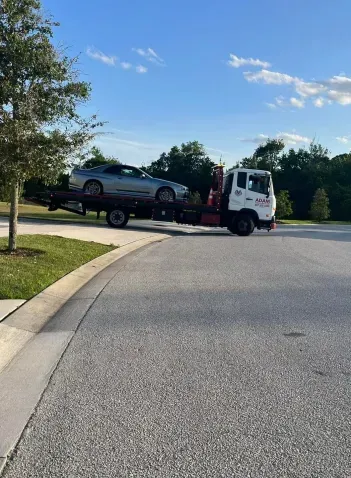 A tow truck is towing a car down a street.