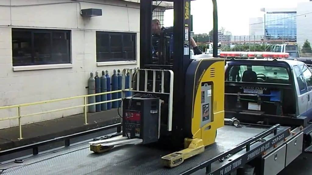 A silver sports car is being towed by a tow truck