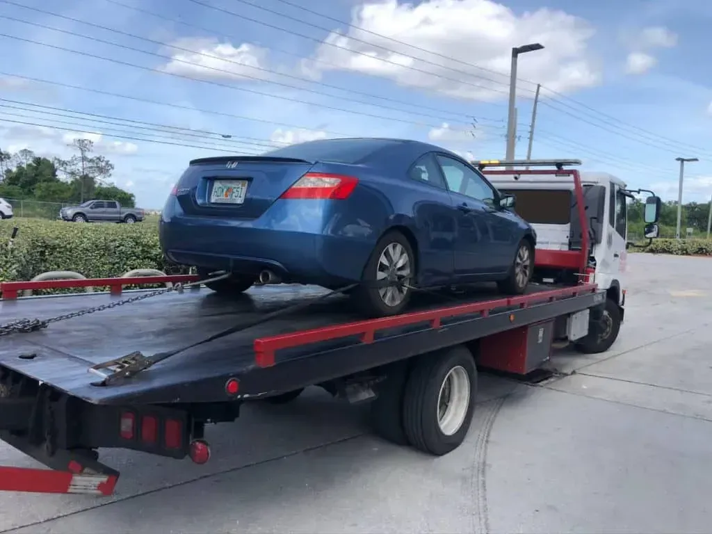 A silver sports car is being towed by a tow truck