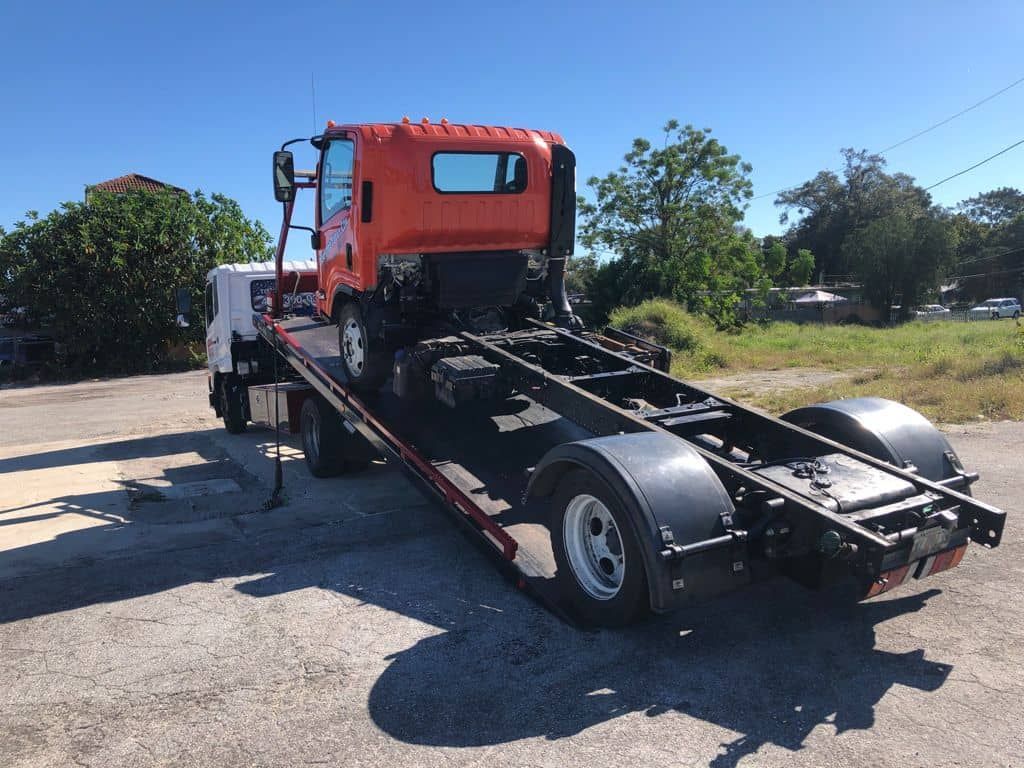 A silver sports car is being towed by a tow truck