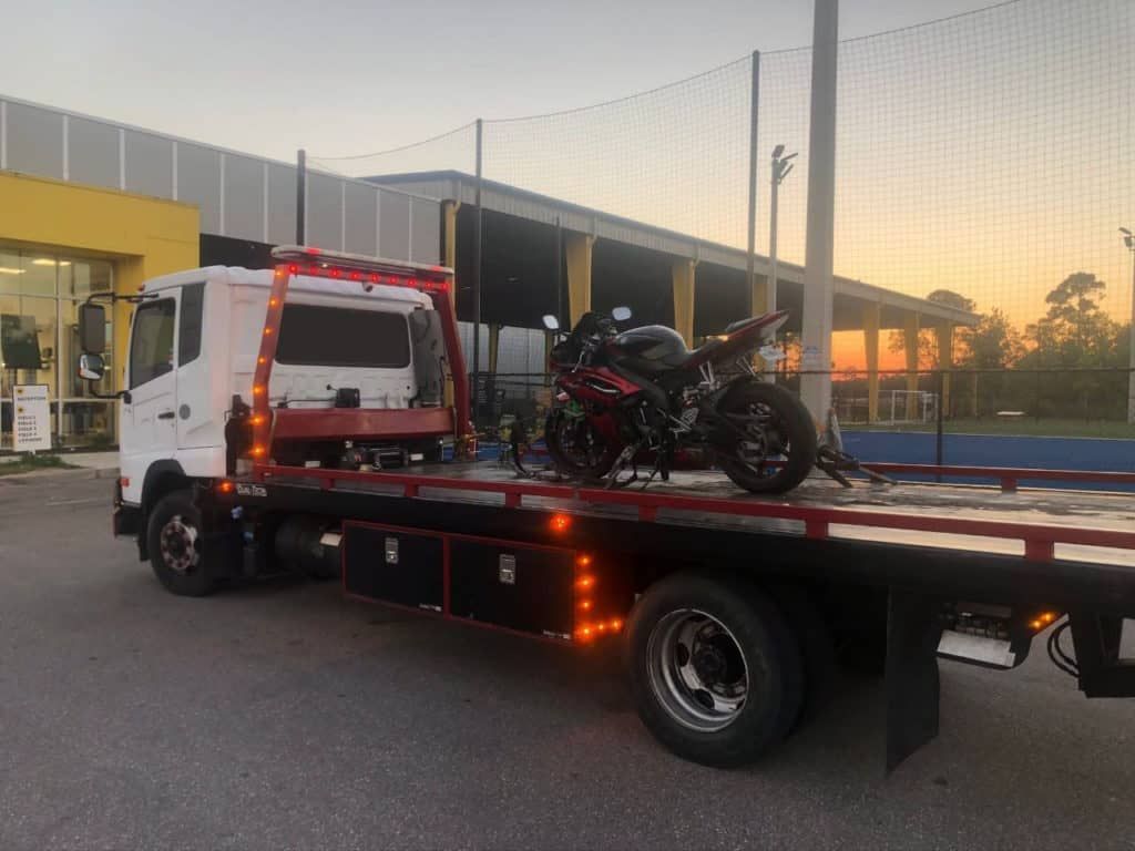 A silver sports car is being towed by a tow truck