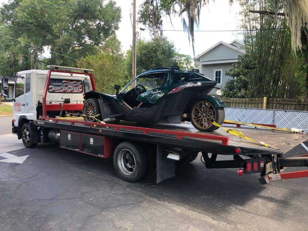 A silver sports car is being towed by a tow truck