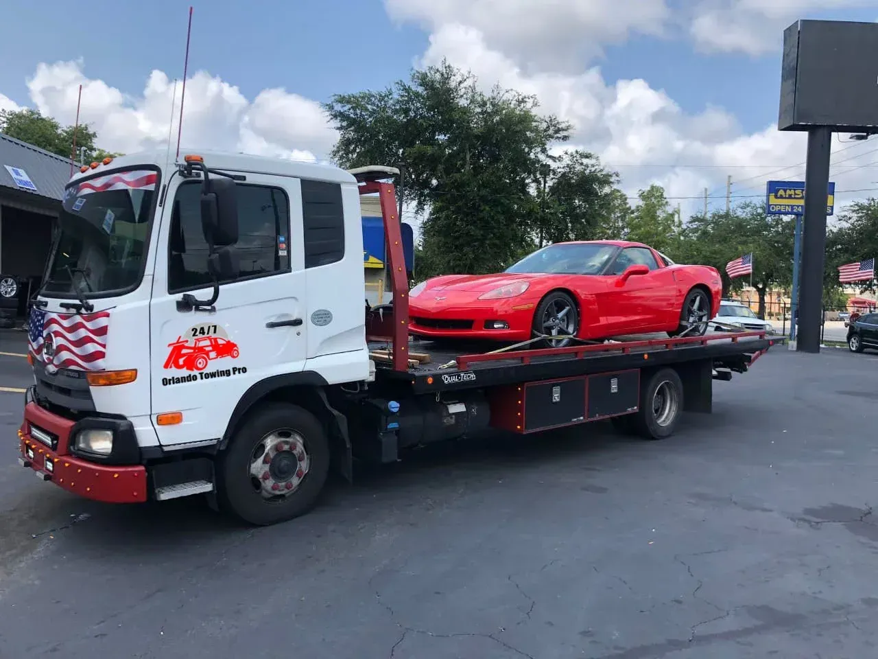 A silver sports car is being towed by a tow truck