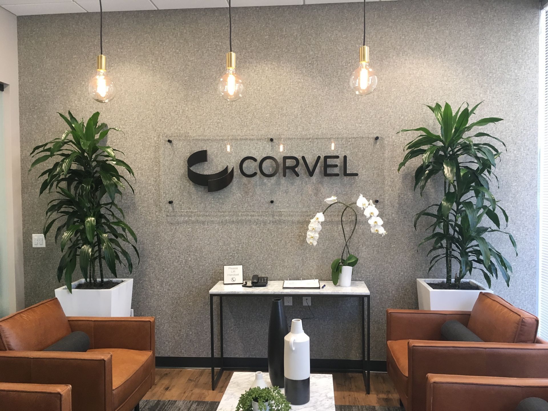 Cozy home office with armchair, desk, plants, and window with blinds.