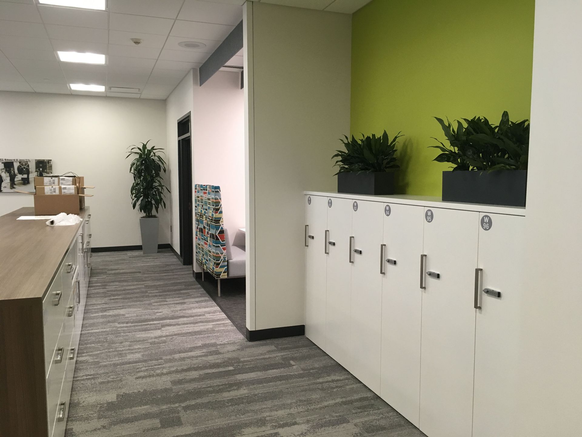 Wooden desk with plants, turquoise chair, and sunlight.