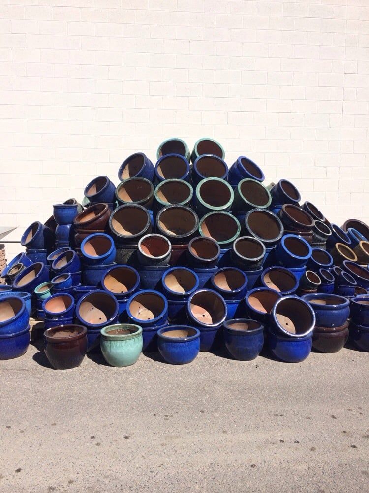 Pile of blue ceramic flower pots against a white wall.