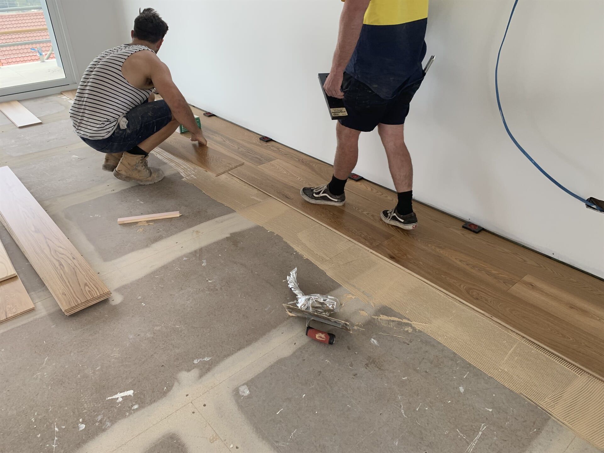 Workers Installing Floorboard in Newly Constructed House — Pacific Flooring in Bonville, NSW