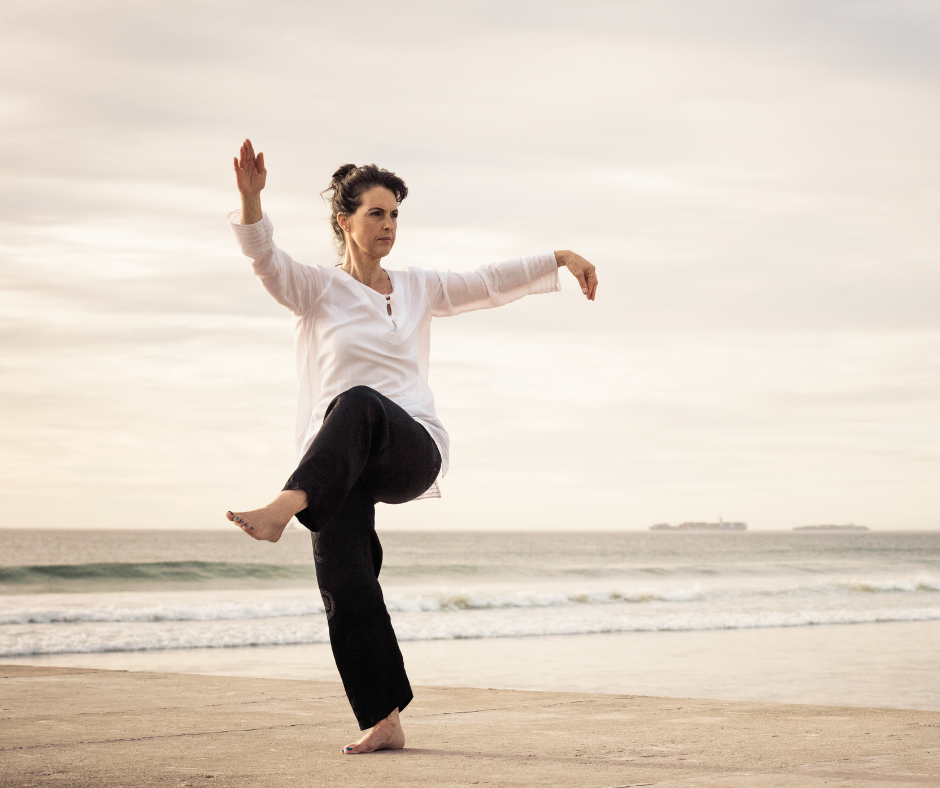 A woman is practicing martial arts on the beach.