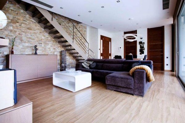 vista interna di soggiorno moderno con pavimento in legno, scala interna, divano e porte interni in legno