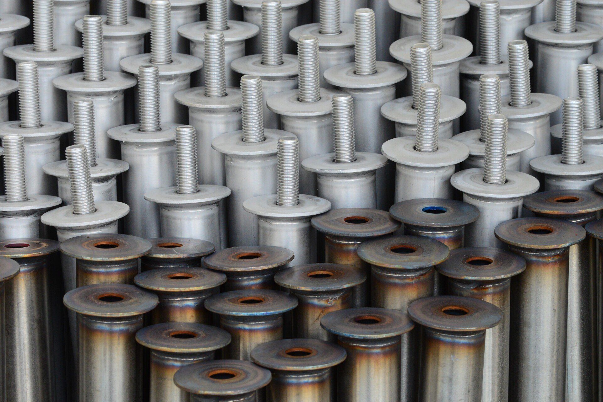 Elementi di fissaggio metallici disposti in file, che mostrano le varie fasi di costruzione.