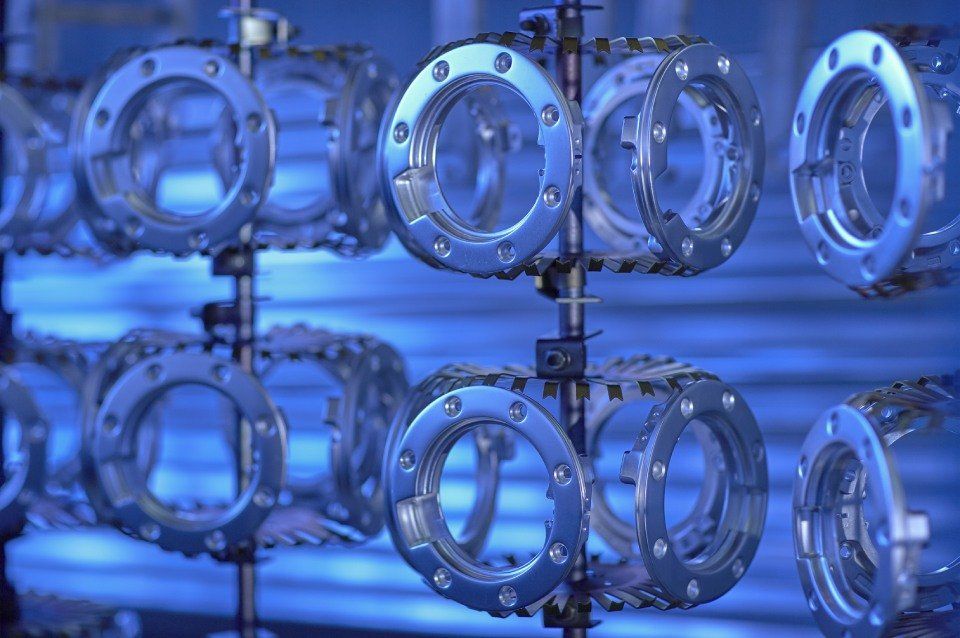 Anelli di metallo su un supporto, rivestiti di azzurro, in un ambiente di produzione.