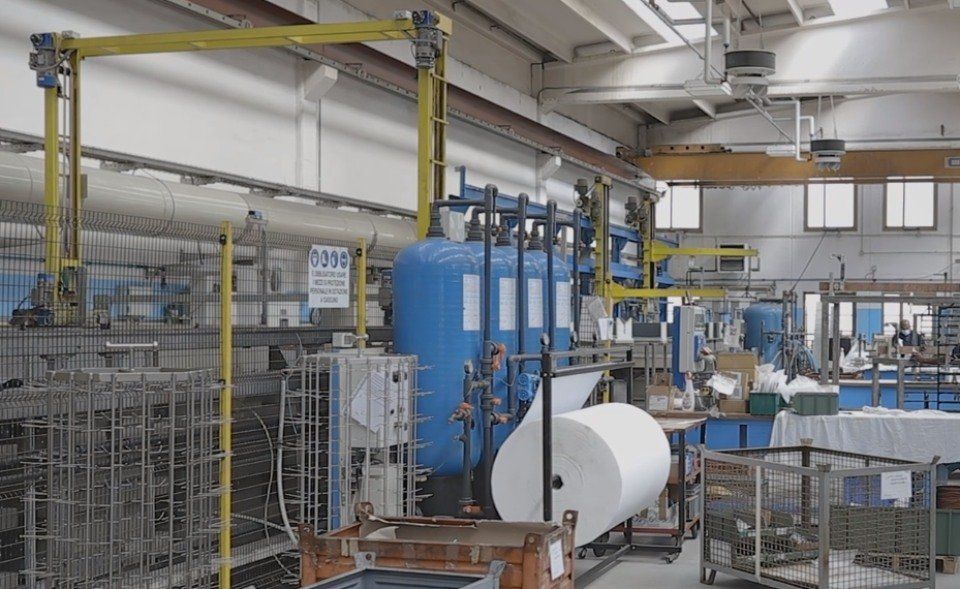 Interno di una fabbrica con grande cisterna blu, rotolo di carta e attrezzatura metallica.