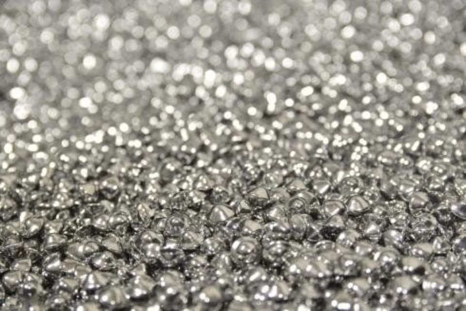 Primo piano di una pila di piccoli pezzi di metallo argentato dalla forma irregolare.