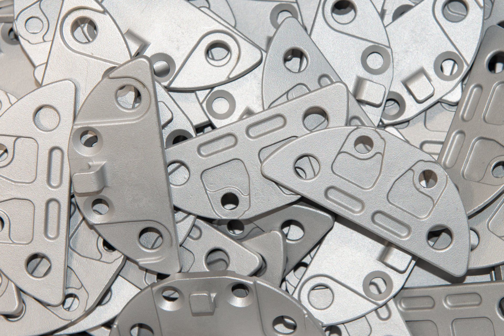 Mucchio di pezzi di metallo dalla forma irregolare con vari fori e ritagli.