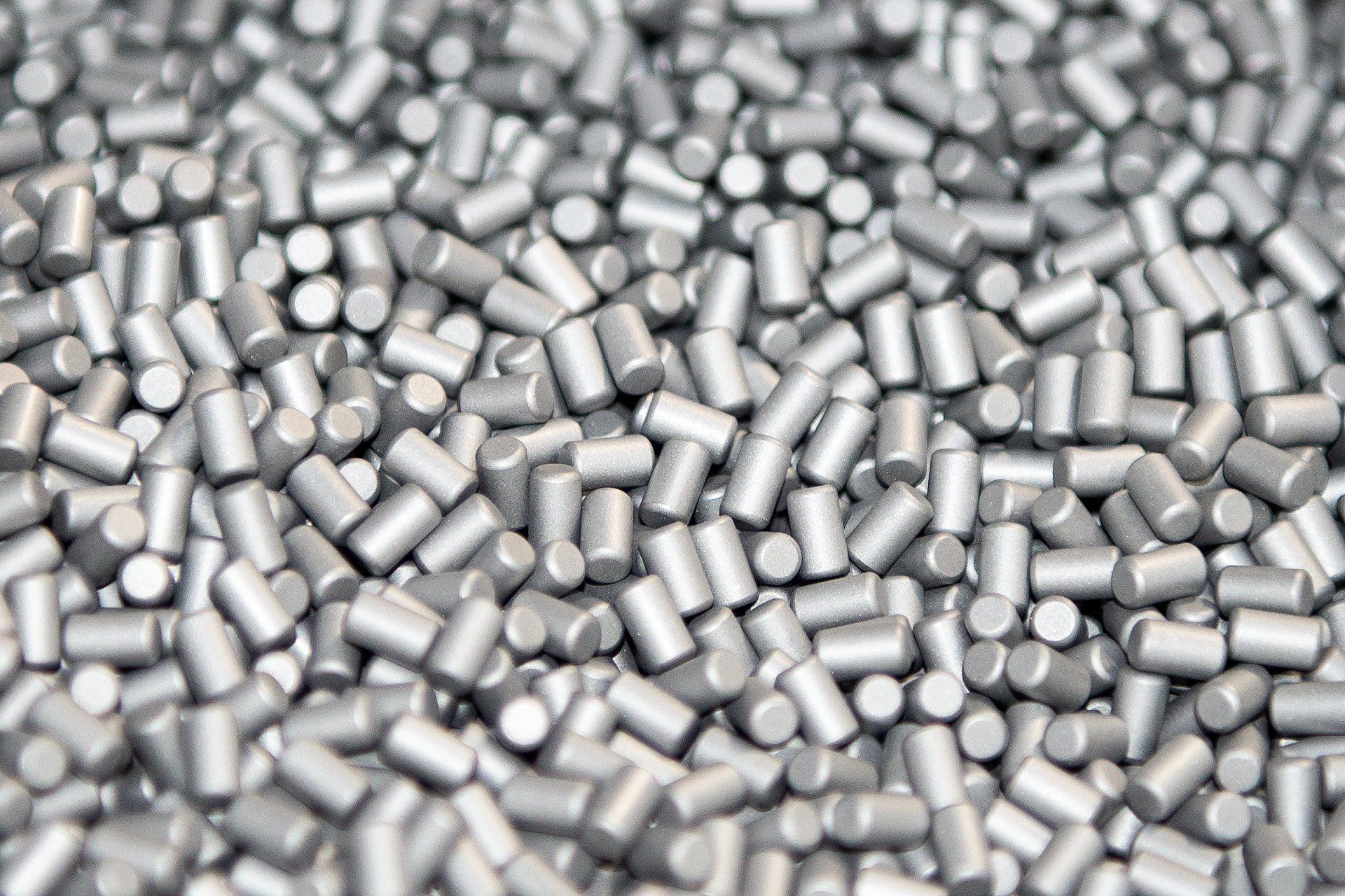 Palline metalliche grigie e cilindriche sparse in un mucchio.