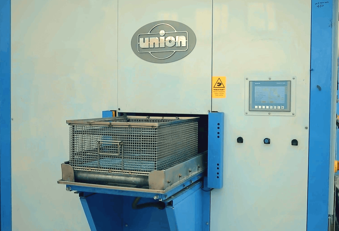Una grande macchina per la pulizia industriale con un cestello metallico all'interno, etichettata 
