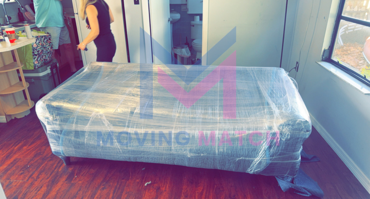 A couch is wrapped in plastic wrap in a living room.