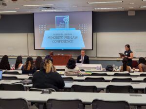 Conference with presenter, attendees, and screen displaying 