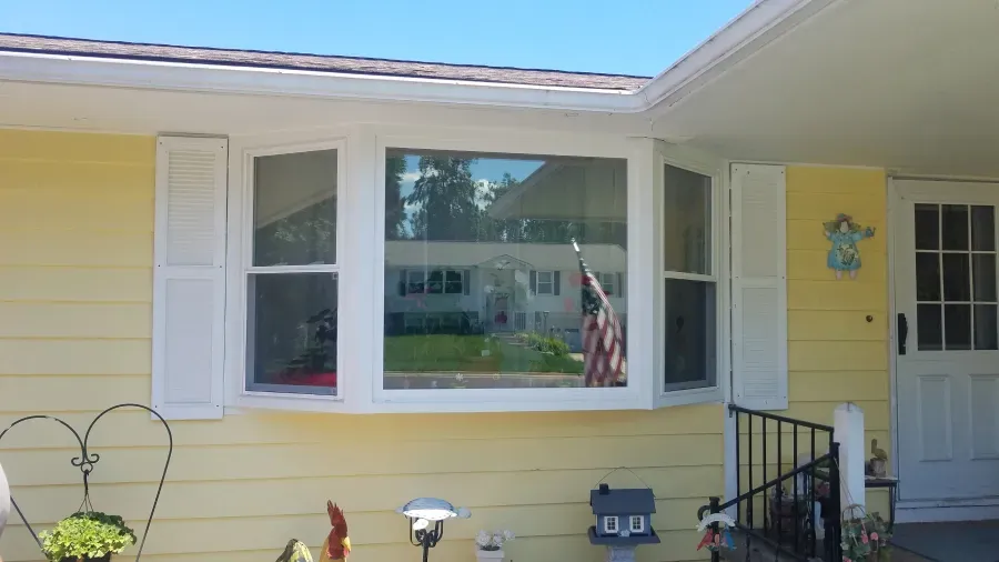 Yellow house with white trim and a bay window.