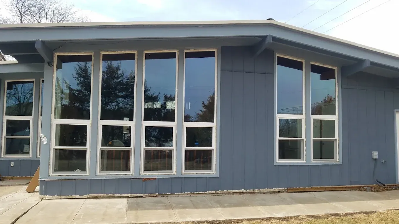 Exterior view of a house with large windows and blue siding.
